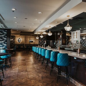 A bar area with multiple seating options, including bar stools and chairs, and a counter with a variety of bottles and glasses. - Hilton Dallas/Southlake Town Square (Southlake)