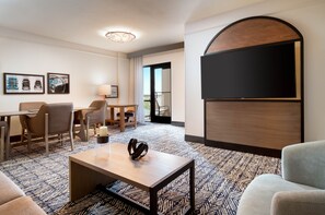 A hotel room with a large bed, a flat-screen TV mounted on the wall, a desk with a chair, a coffee table, and a patterned carpet. - Hilton Dallas/Southlake Town Square (Southlake)