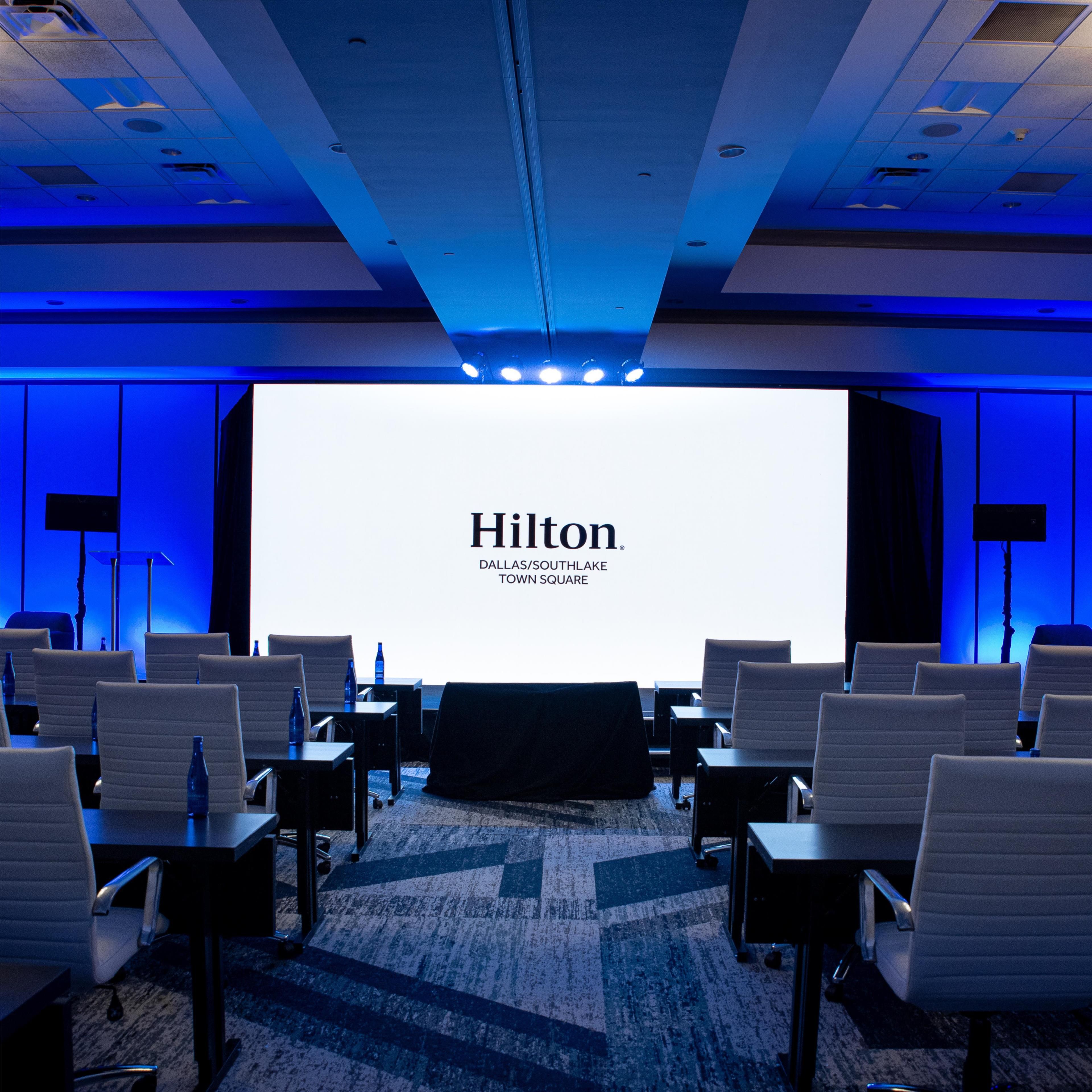 A conference room with a large screen displaying 'Hilton Dallas/Southlake Town Square'.