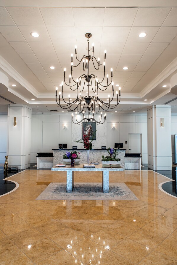 A spacious lobby with a large chandelier, marble flooring, and a reception desk with a vase of flowers. - Hilton Dallas/Southlake Town Square (Southlake)