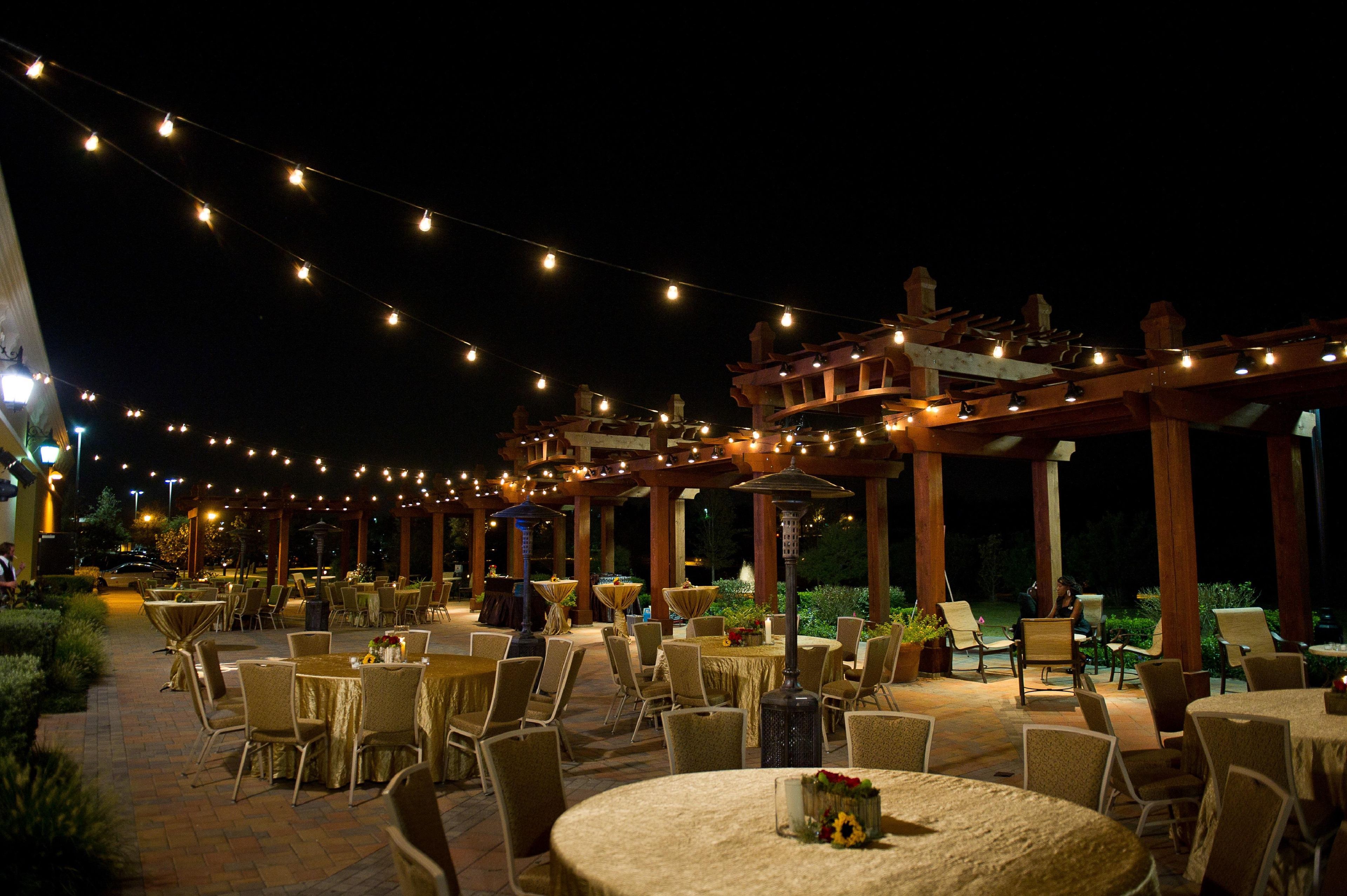 An outdoor dining area with string lights, tables, and chairs.