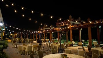 An outdoor dining area with string lights, tables, and chairs.