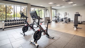 A gym with cardio machines, dumbbells, and a treadmill.