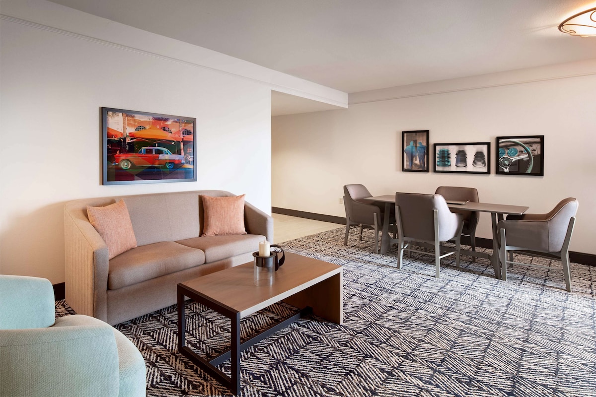 A modern living room with a sofa, coffee table, and dining area with chairs and a table.