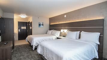 Habitación de hotel con dos camas, un escritorio y un mando a distancia, y una lámpara fijada a la pared.