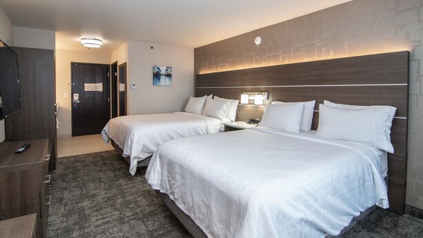 A hotel room with two beds, a desk with a chair, a dresser, and a nightstand with a lamp. - Holiday Inn Express Kalispell by IHG (Kalispell)