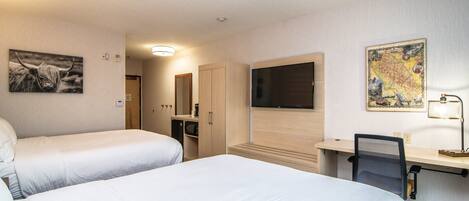 A hotel room with two beds, a desk with a chair, a TV, and artwork on the walls.