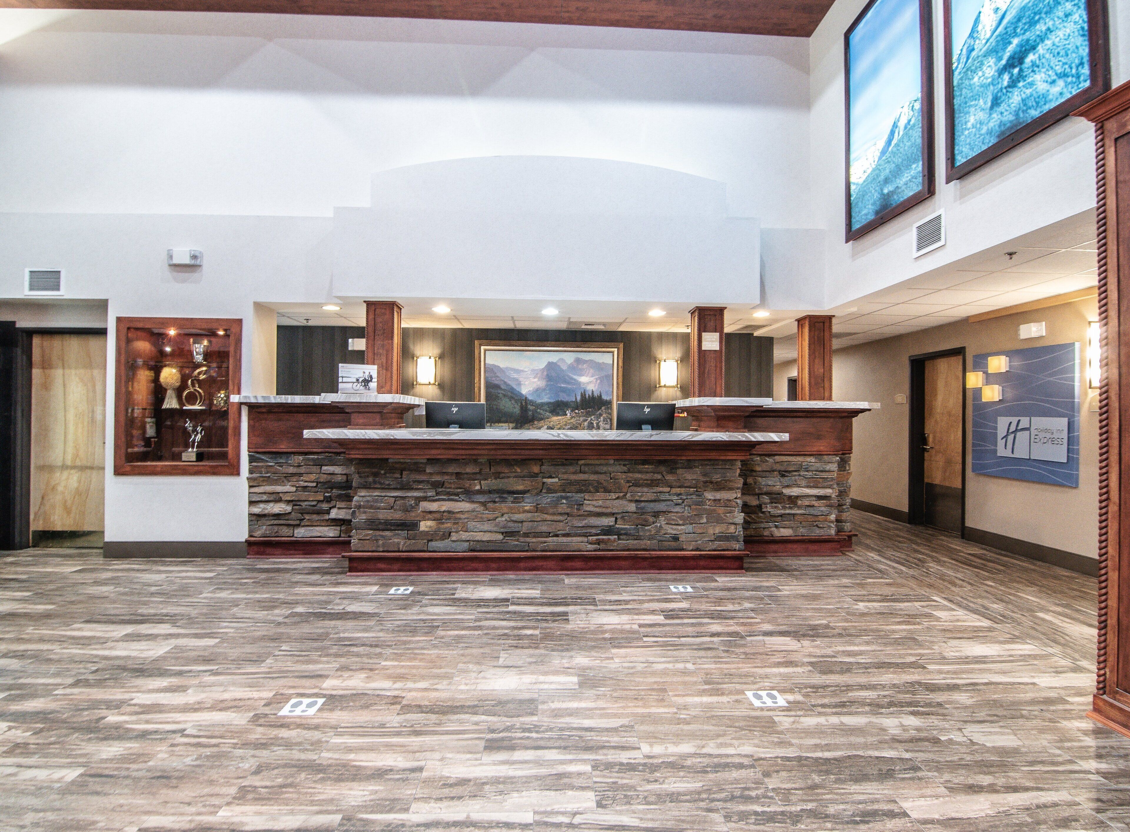 A reception desk with a stone base, a wooden counter, and a mountain landscape painting above.