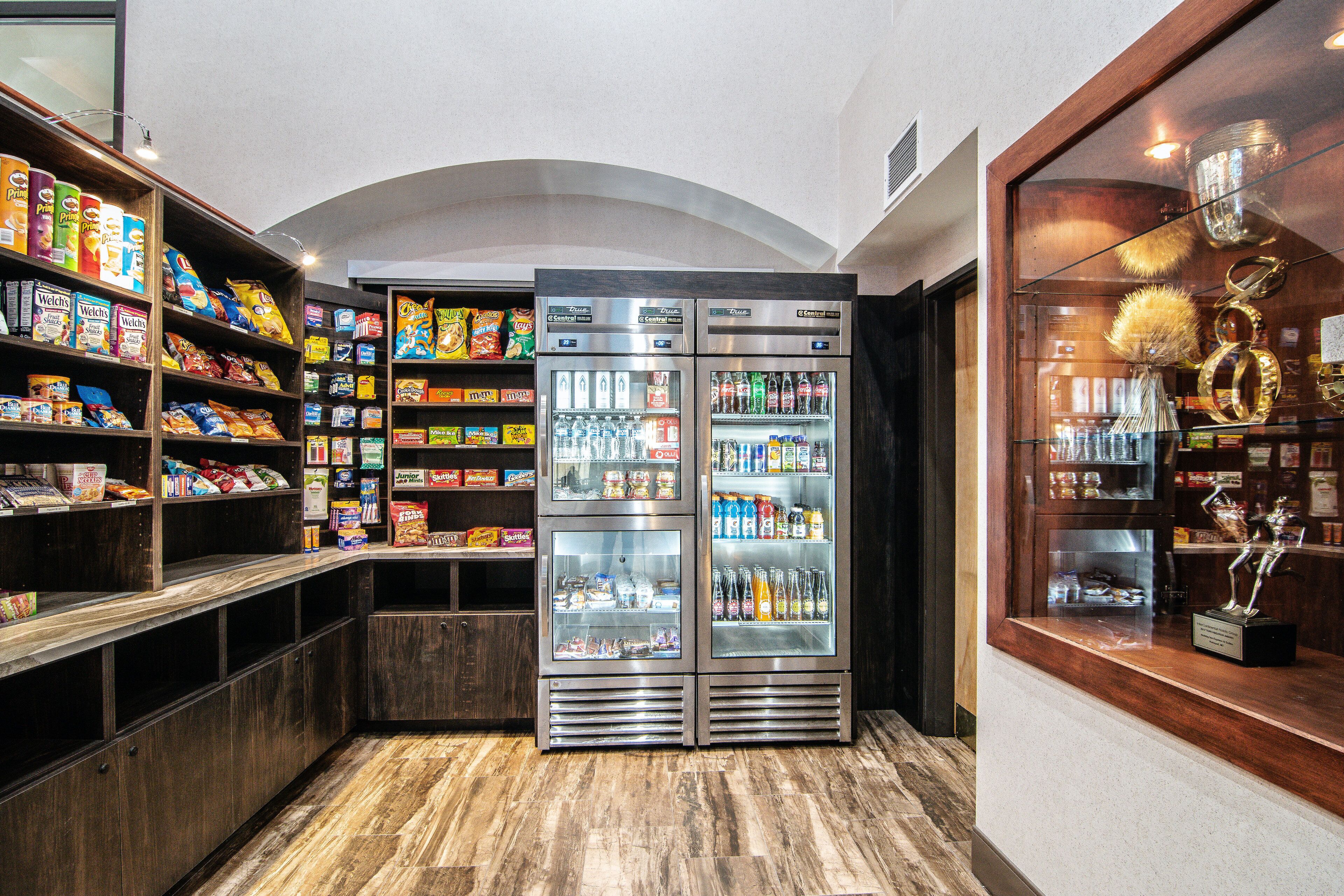 Un espace de vente en libre-service proposant des collations et des boissons, avec plusieurs étagères remplies de divers en-cas et un compartiment réfrigéré pour les boissons.