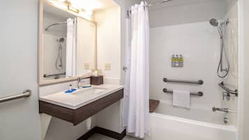 Un baño con bañera, ducha, lavabo con espejo y un perchero para toallas.