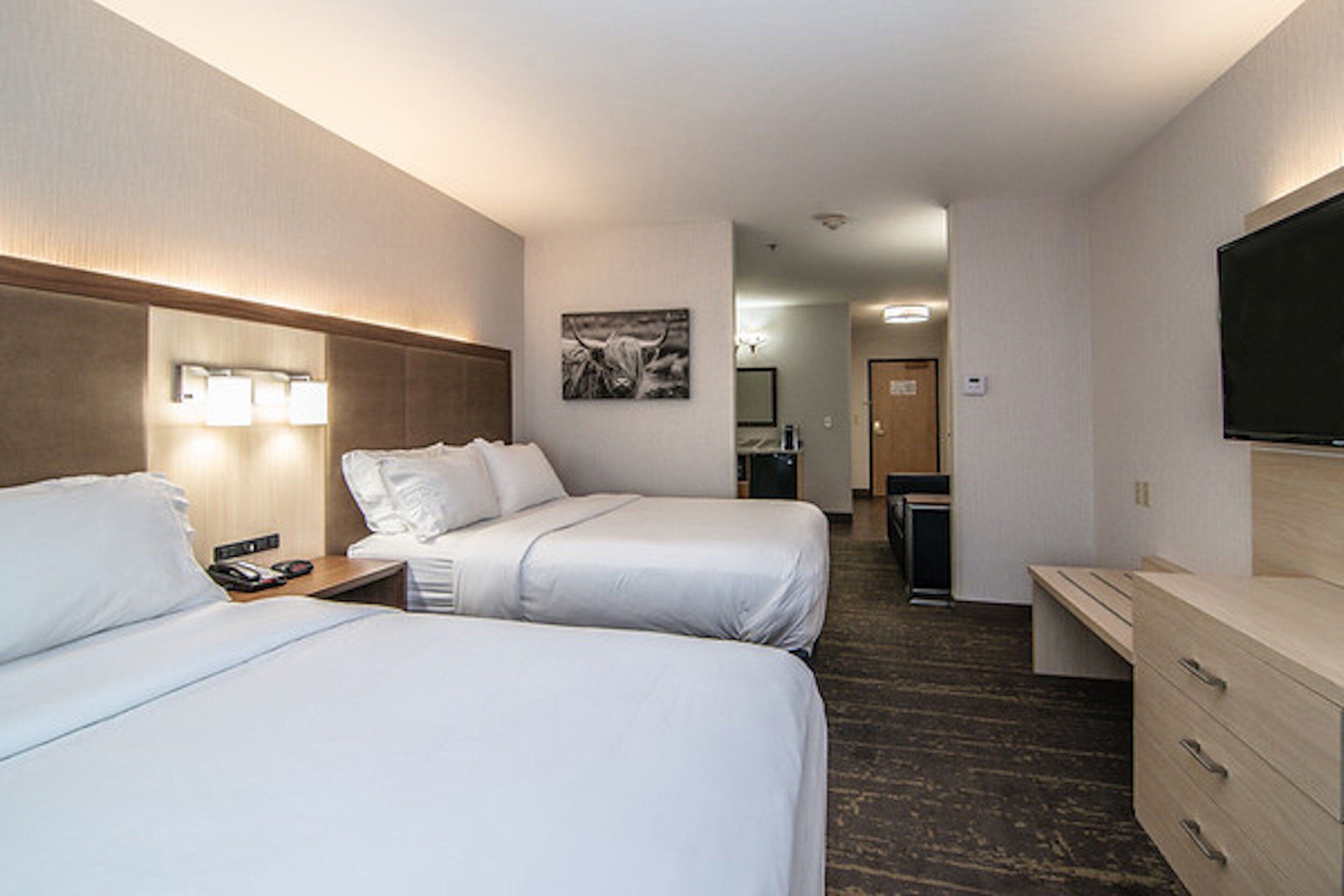 Une chambre d’hôtel avec deux lits, un bureau, une télévision et une salle de bain visible au fond.