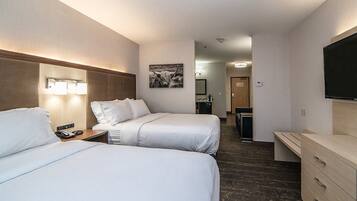 Une chambre d’hôtel avec deux lits, un bureau, une télévision et une salle de bain visible au fond.