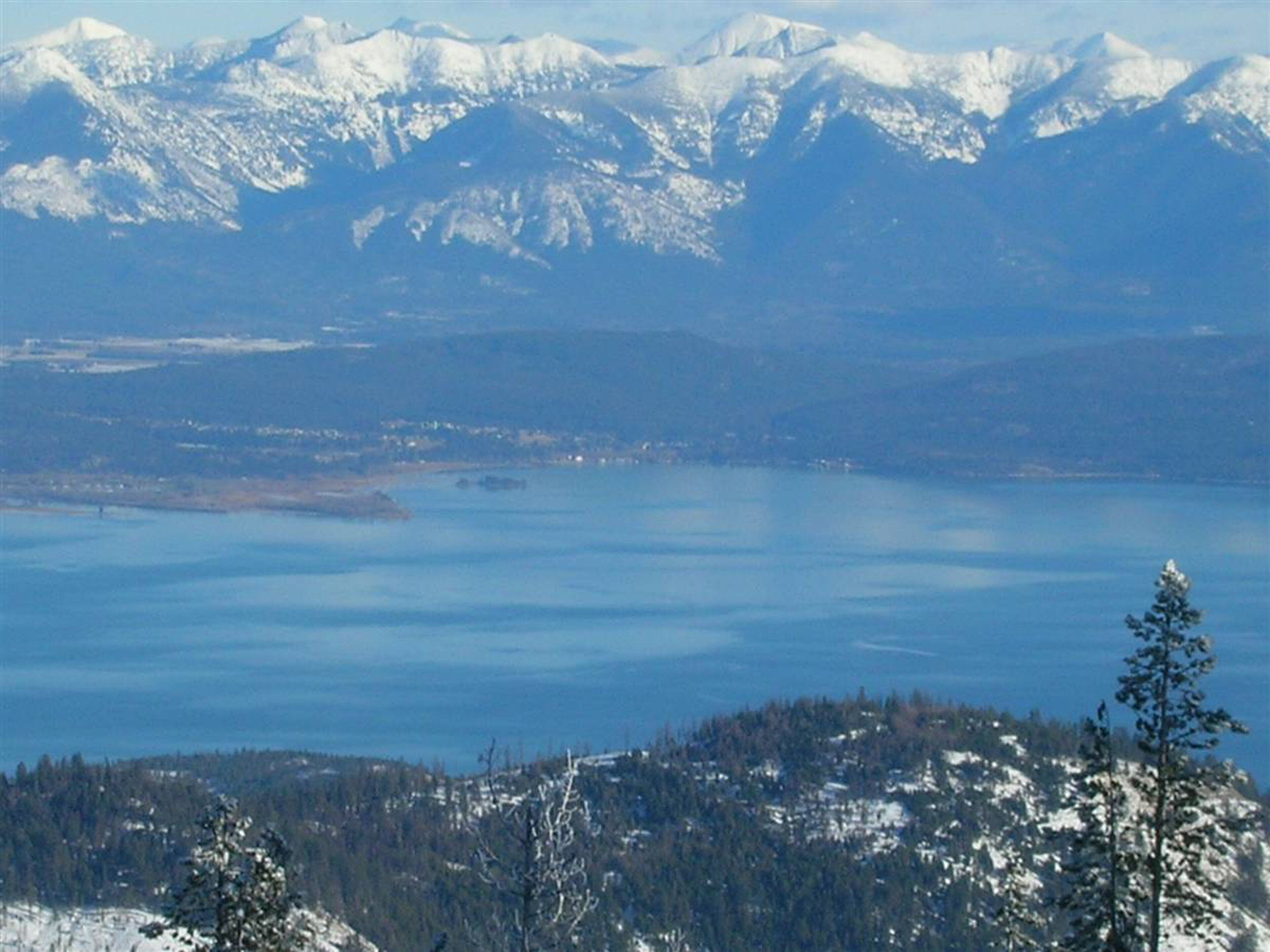 A mountainous landscape with a lake and snow-covered peaks.