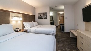 A hotel room with two beds, a desk, a TV, and a bathroom in the background. - Holiday Inn Express Kalispell by IHG (Kalispell)