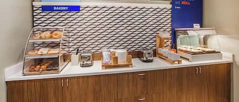 A breakfast buffet counter with a bakery section and a display for breakfast items.