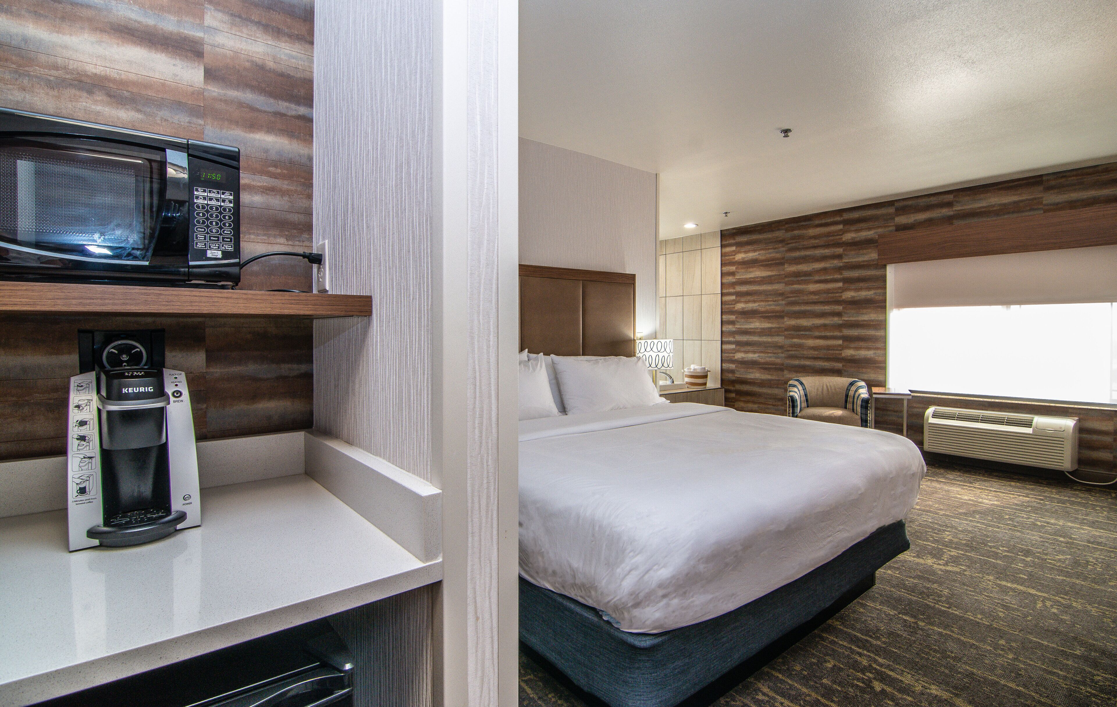 Habitación de hotel con cama, microondas, cafetera y ventana.