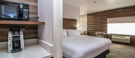 Habitación de hotel con cama, microondas, cafetera y ventana.