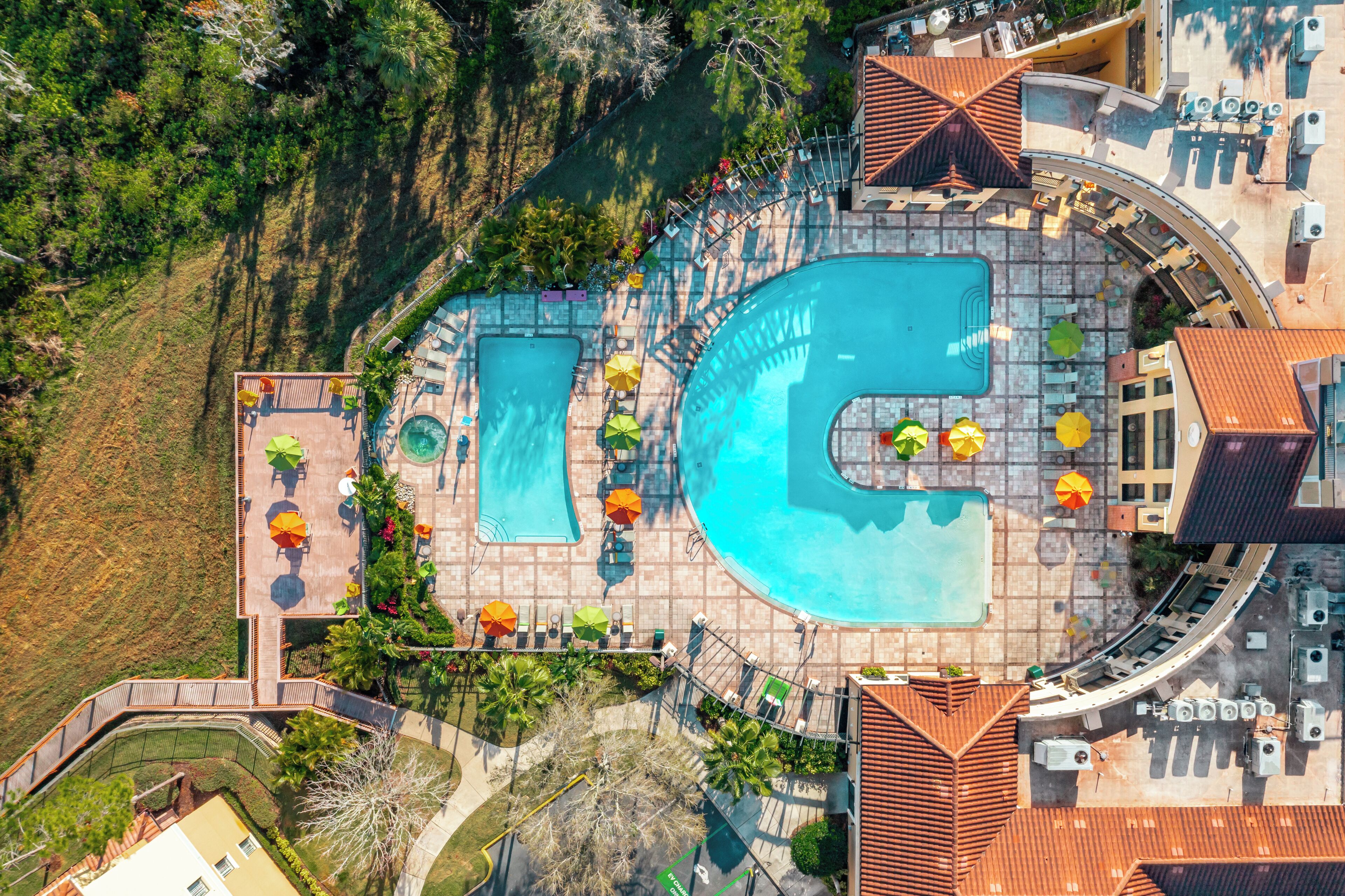 Vista aérea de un complejo turístico con varias piscinas, tumbonas y sombrillas.