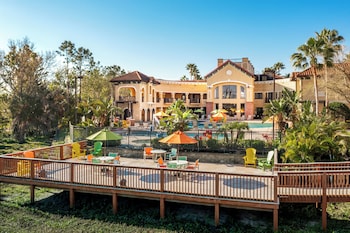 A hotel room with a sofa, a dining table, two chairs, a ceiling fan, a TV, and a balcony with a view. at The Berkley, Orlando