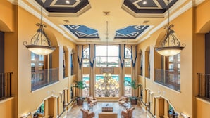 A spacious lobby with a high ceiling, chandeliers, and a view of the outdoors.