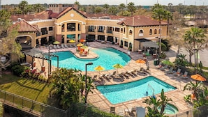 A resort with a large pool, outdoor seating, and a covered area.