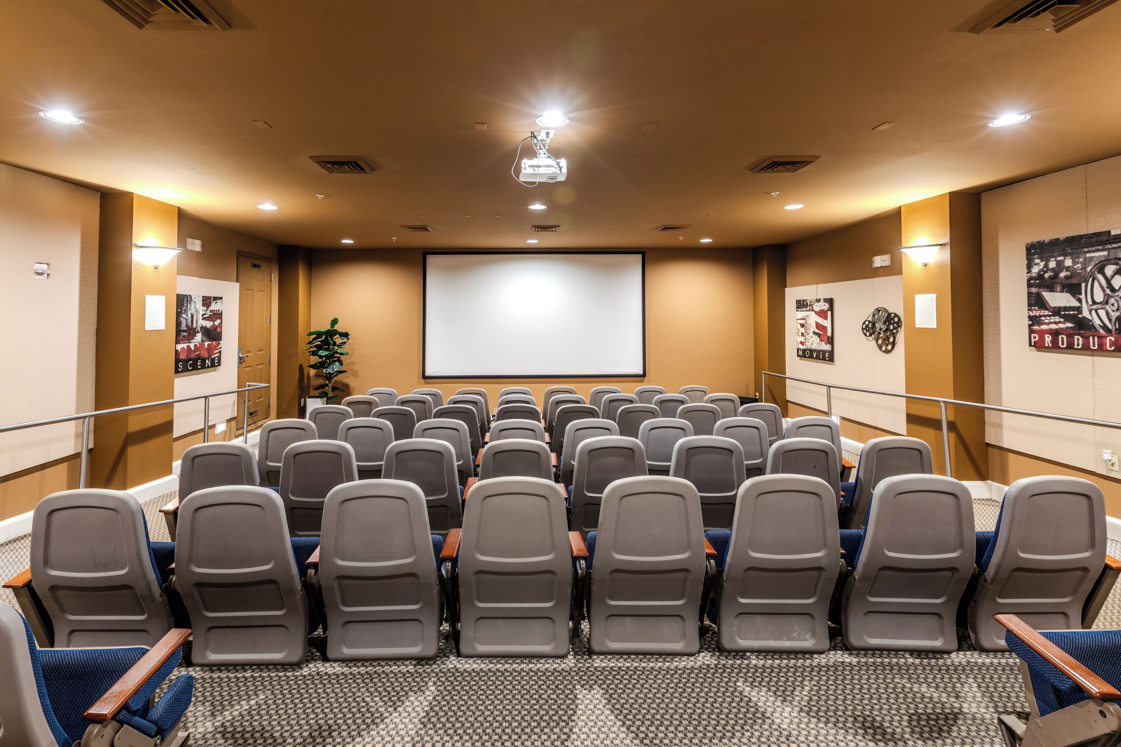 A conference room with rows of chairs, a large screen, and a projector.