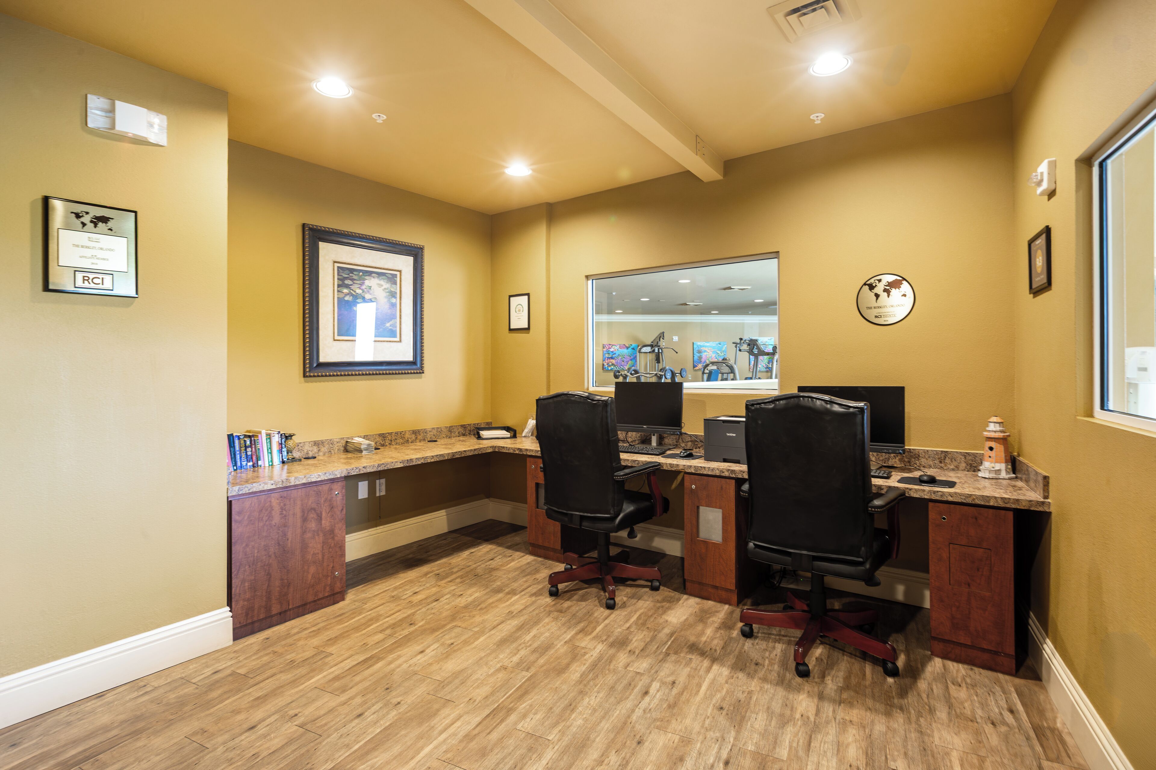 A home office with two desks, chairs, and a large window.