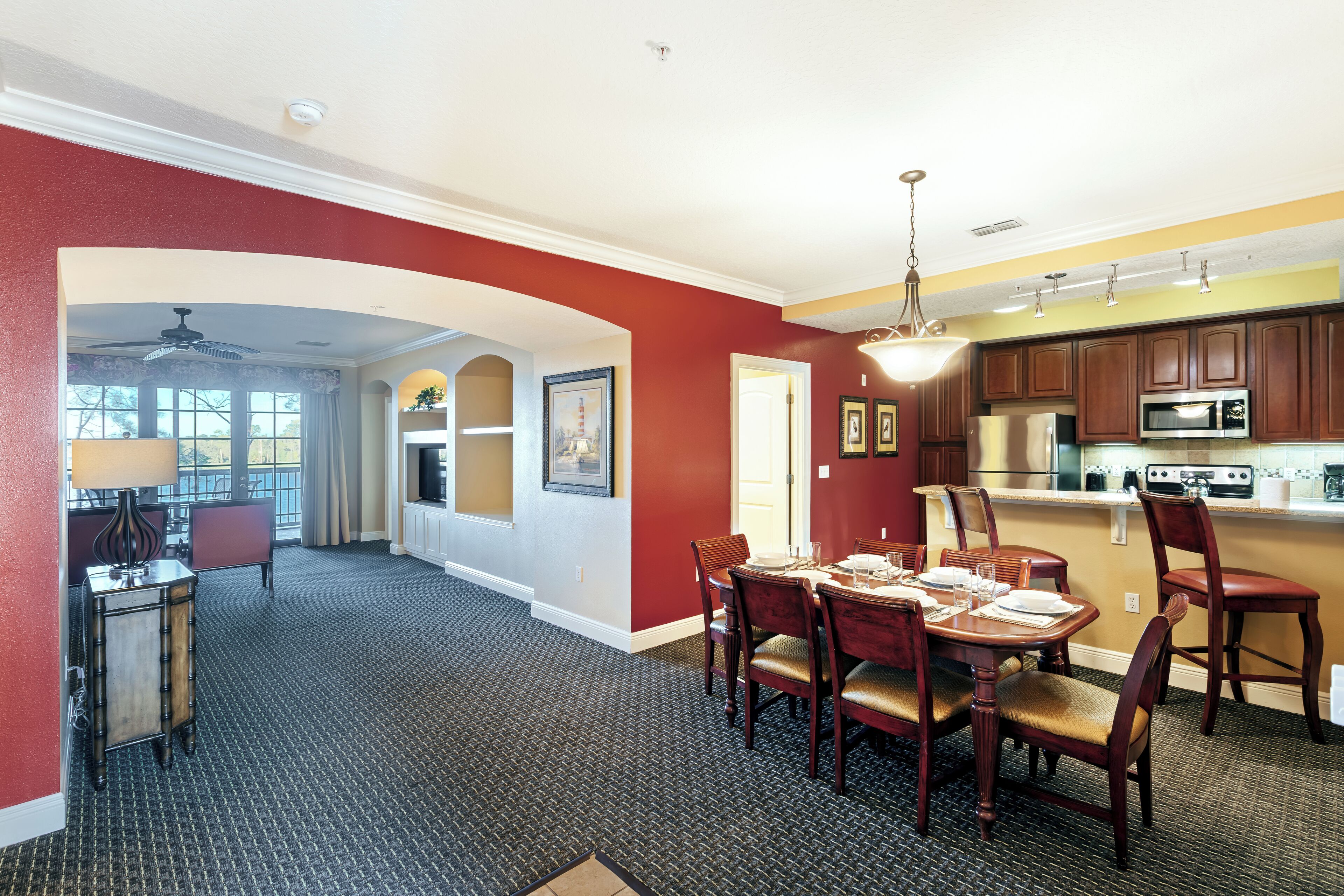 A spacious dining area with a high ceiling and a view to a balcony.