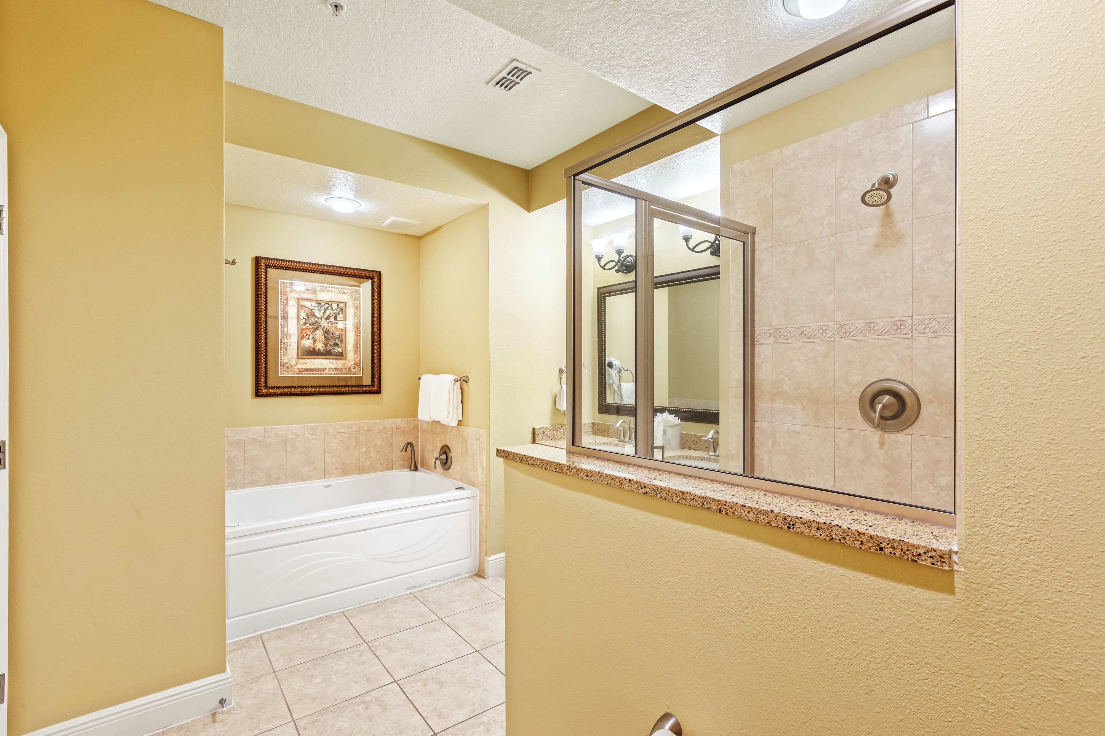 A bathroom with a bathtub, a large mirror, and a shower area.