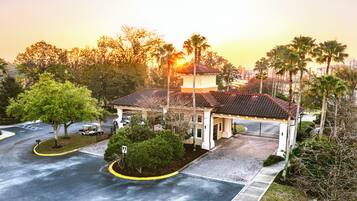 A building with a tiled roof, surrounded by trees and a parking area.