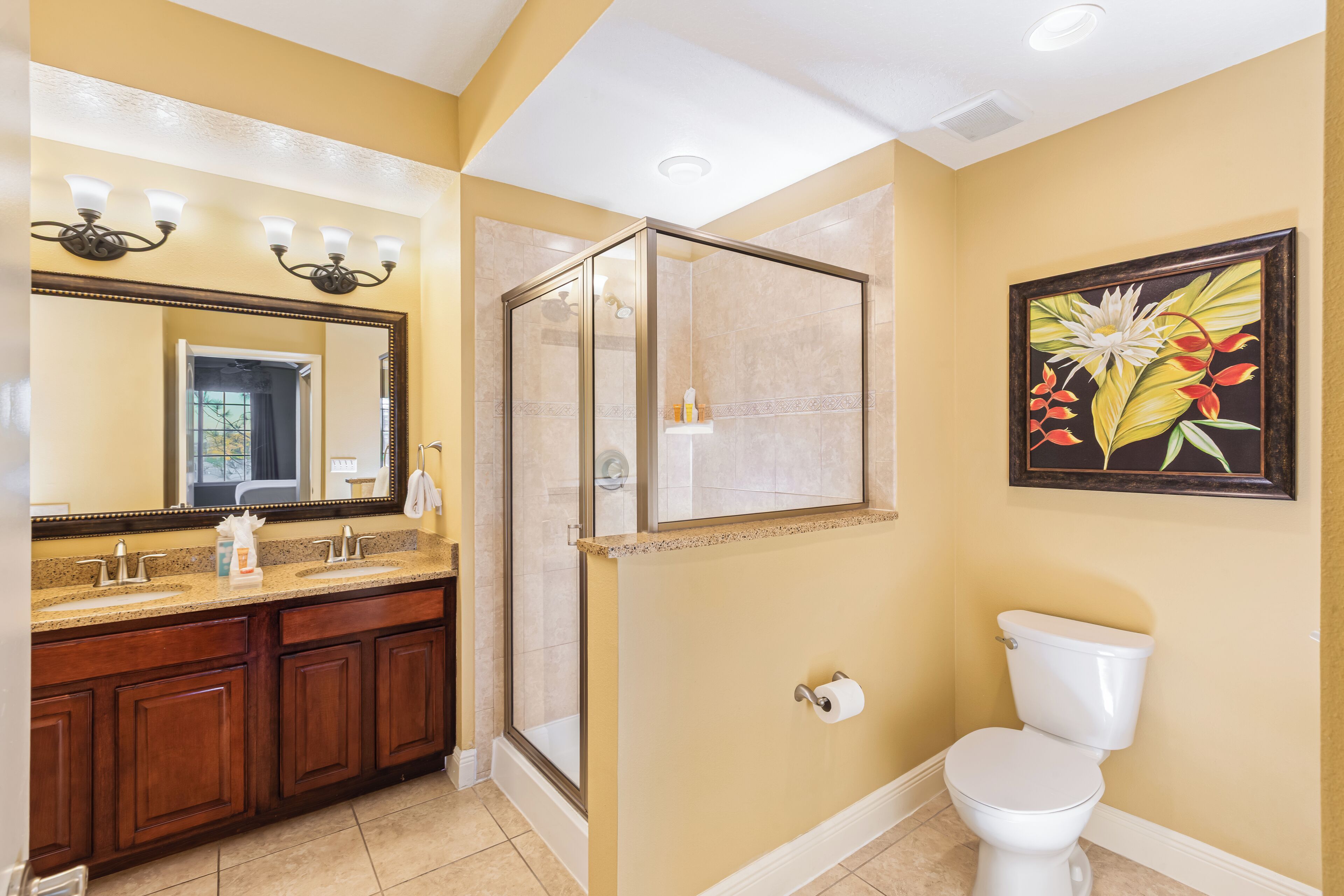 A bathroom with a large mirror, a shower enclosure, a toilet, and a sink with a vanity.