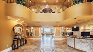 A spacious lobby with a curved staircase, a reception desk, and a large mirror.