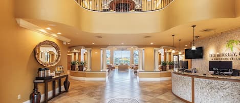 A spacious lobby with a curved staircase, a reception desk, and a large mirror.