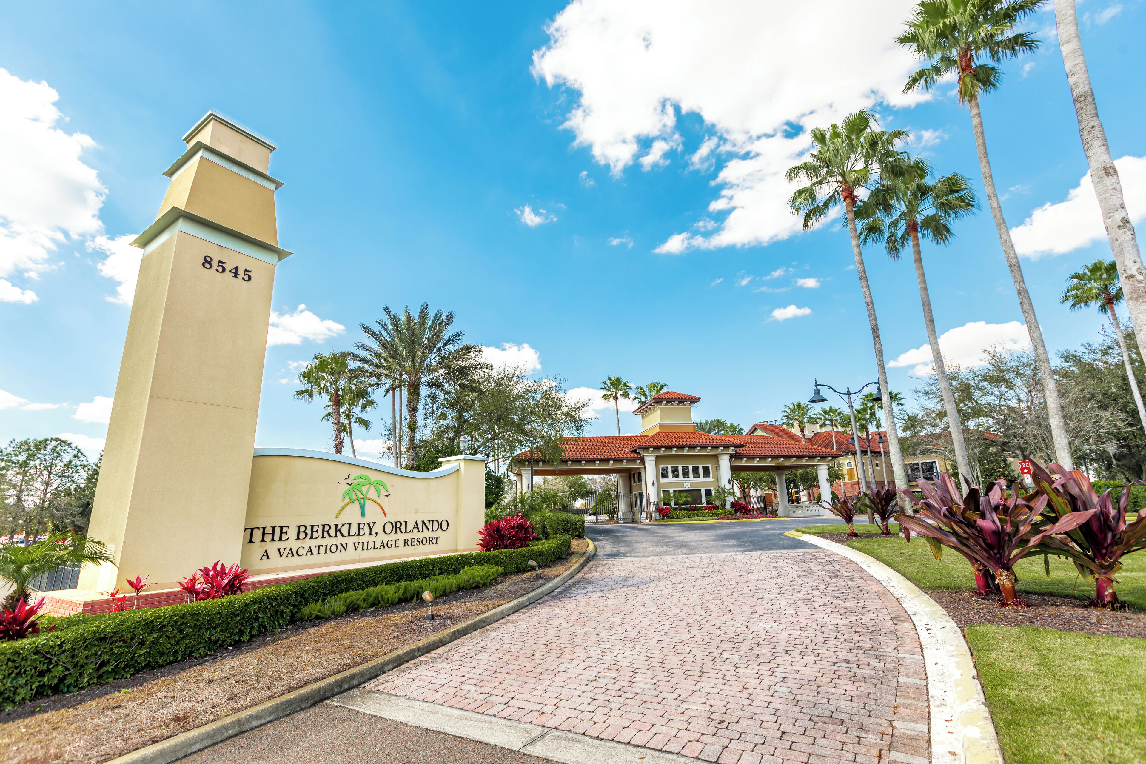 Entrada de un resort con un cartel que dice "The Berkeley, Orlando, A Vacation Village Resort" y un camino de ladrillo que lleva al edificio.