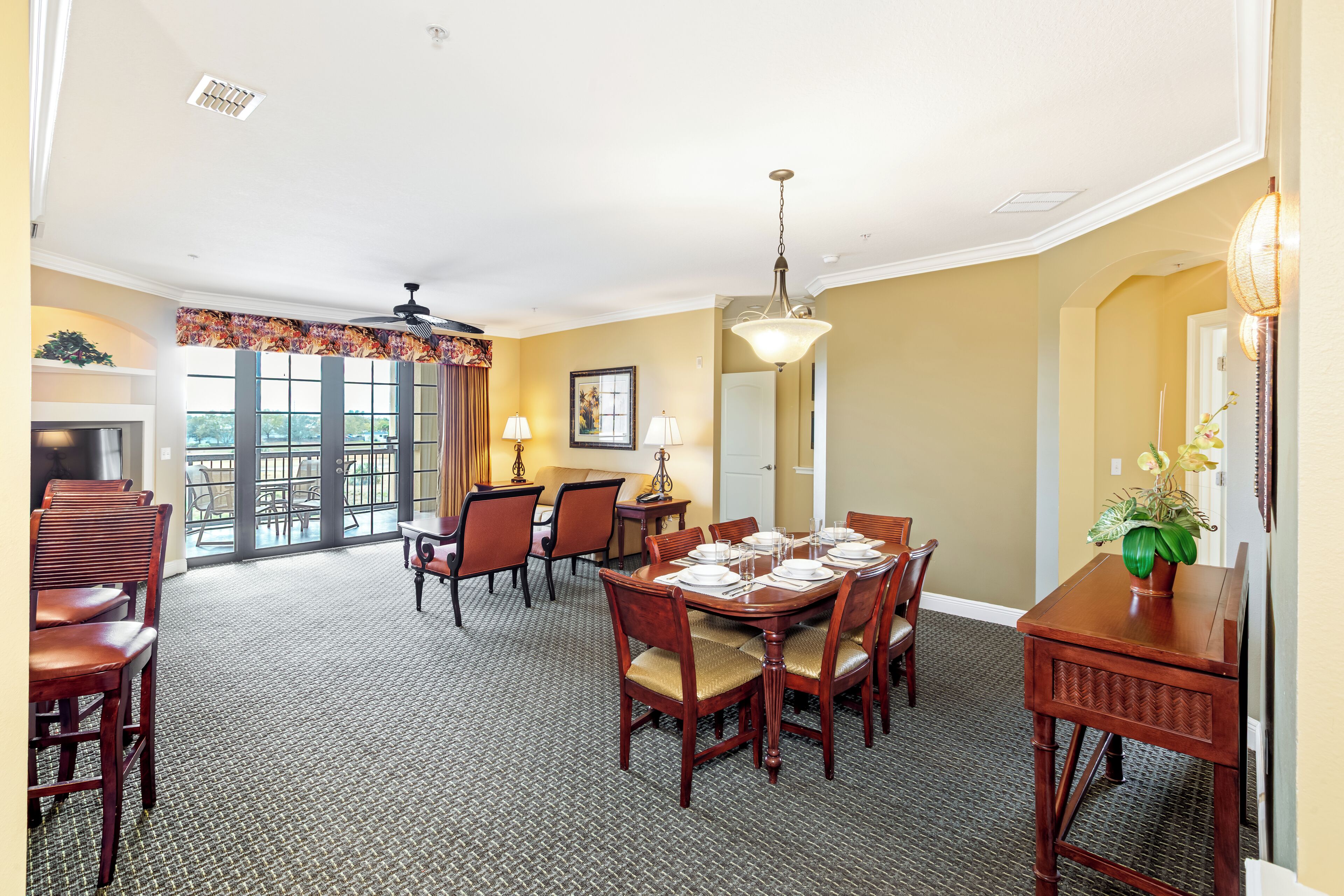 A dining area with a high ceiling, a chandelier, and a view through large windows.
