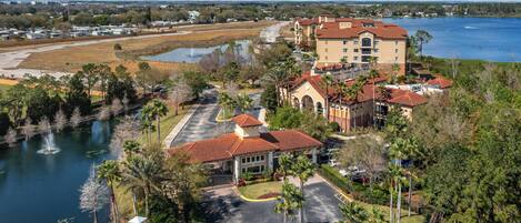 A hotel with a central courtyard, a lake, and a parking area.