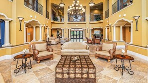 A spacious lobby with a central seating area, a chandelier, and a view of the entrance.