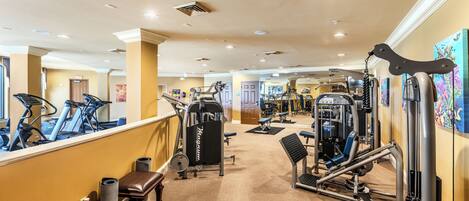 A gym with treadmills, weight machines, and a mirror wall.
