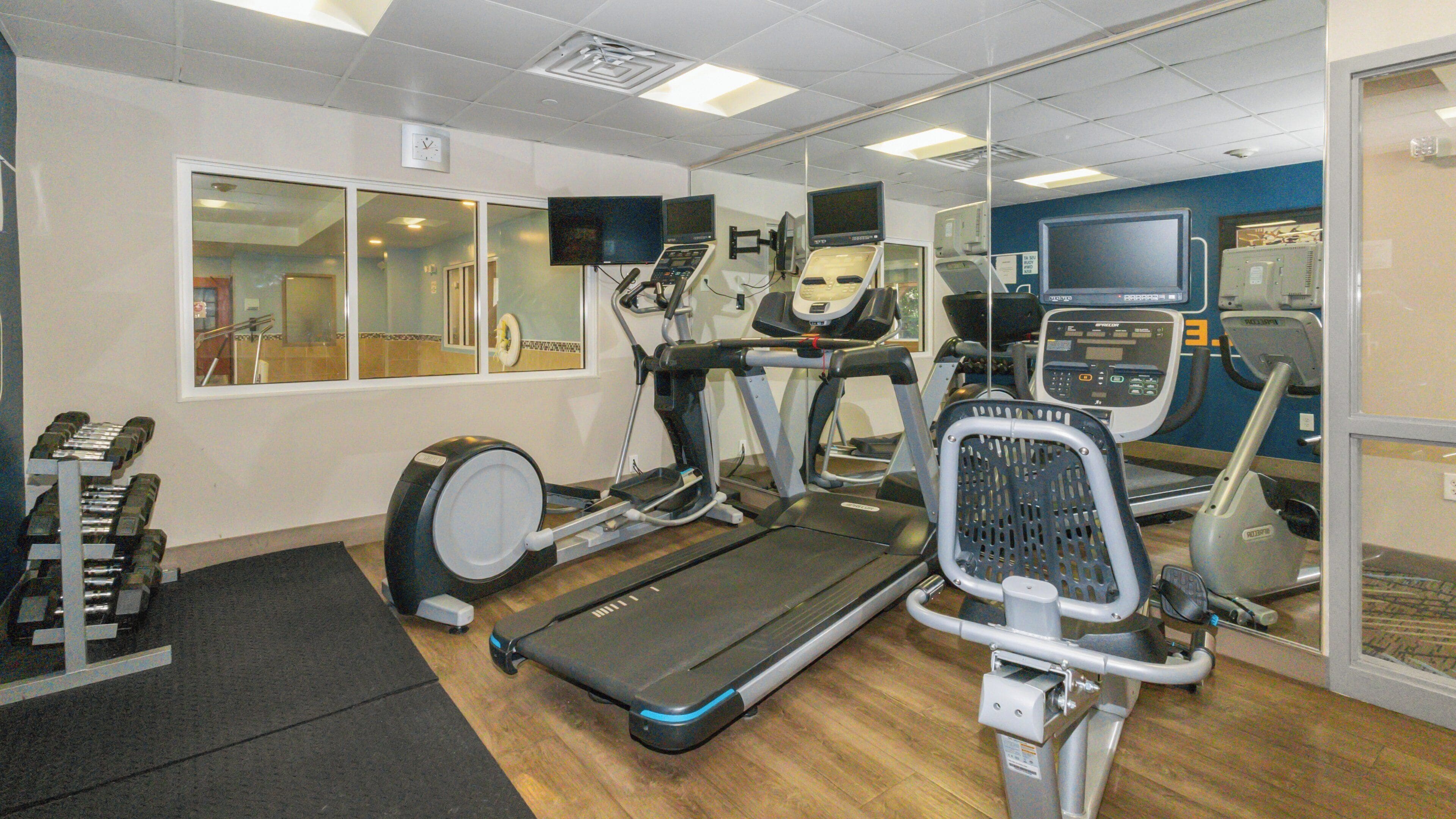 A gym with treadmills, elliptical machines, and free weights.