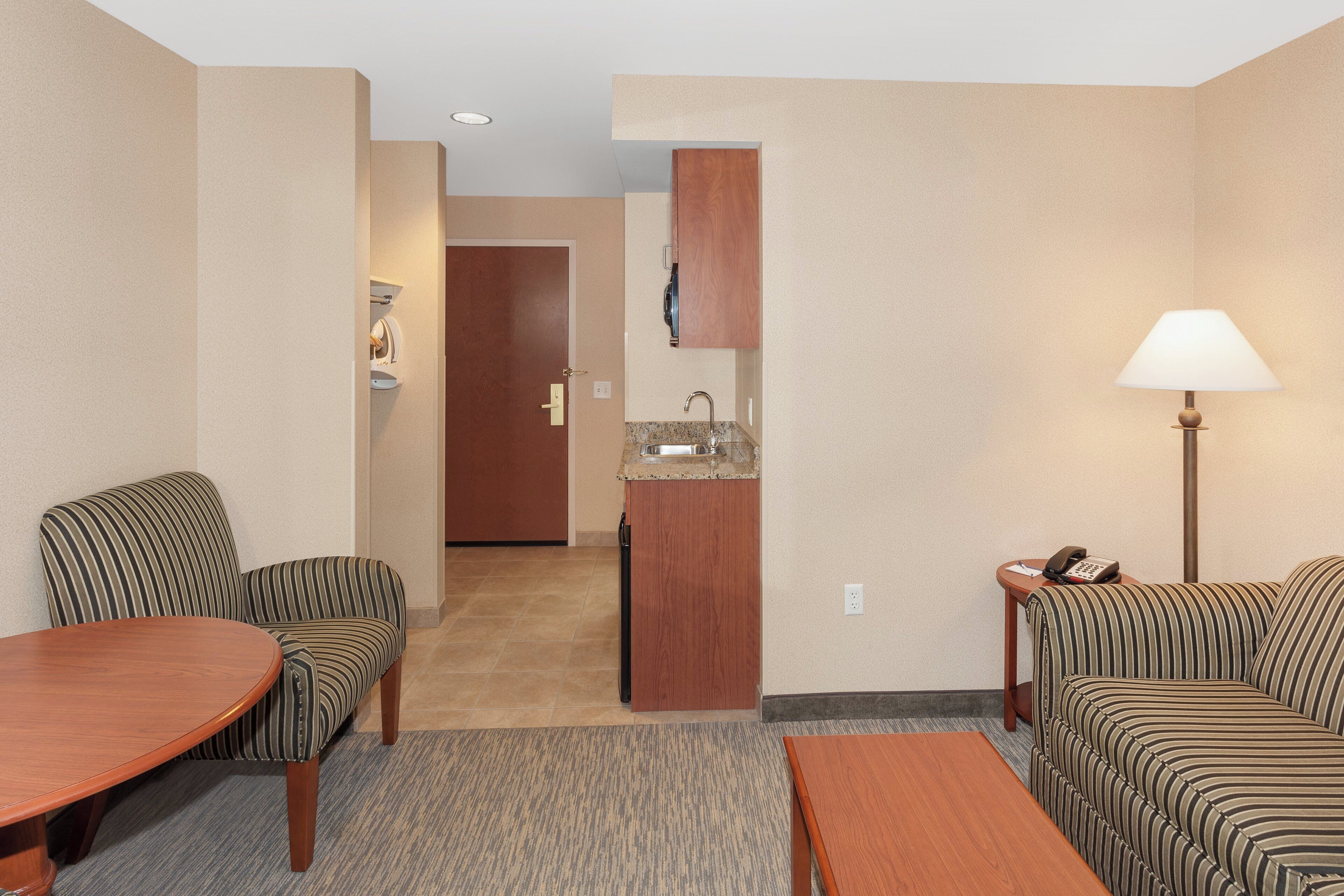A hotel room with a kitchenette, a dining area with a table and chairs, and a living area with a sofa.