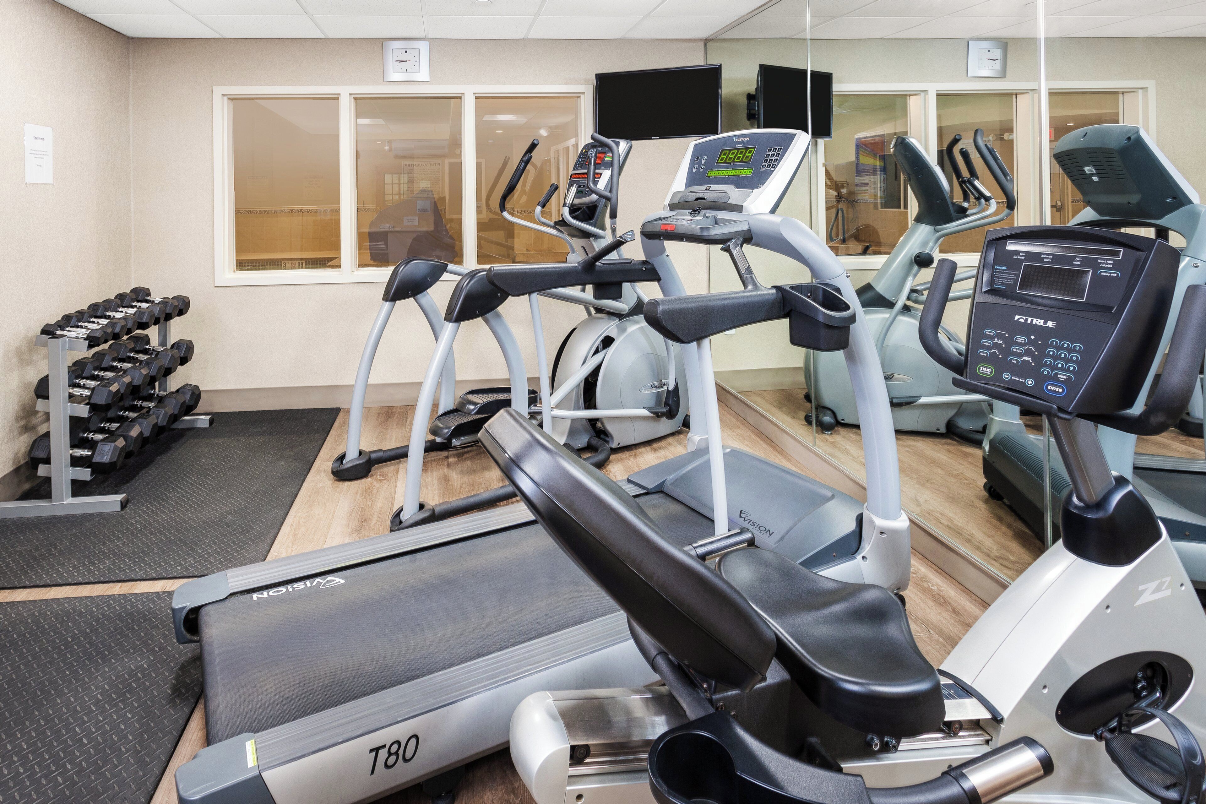 Une salle de sport équipée de tapis de course, d’un vélo d’appartement et d’un banc de musculation.
