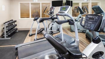 Une salle de sport équipée de tapis de course, d’un vélo d’appartement et d’un banc de musculation.