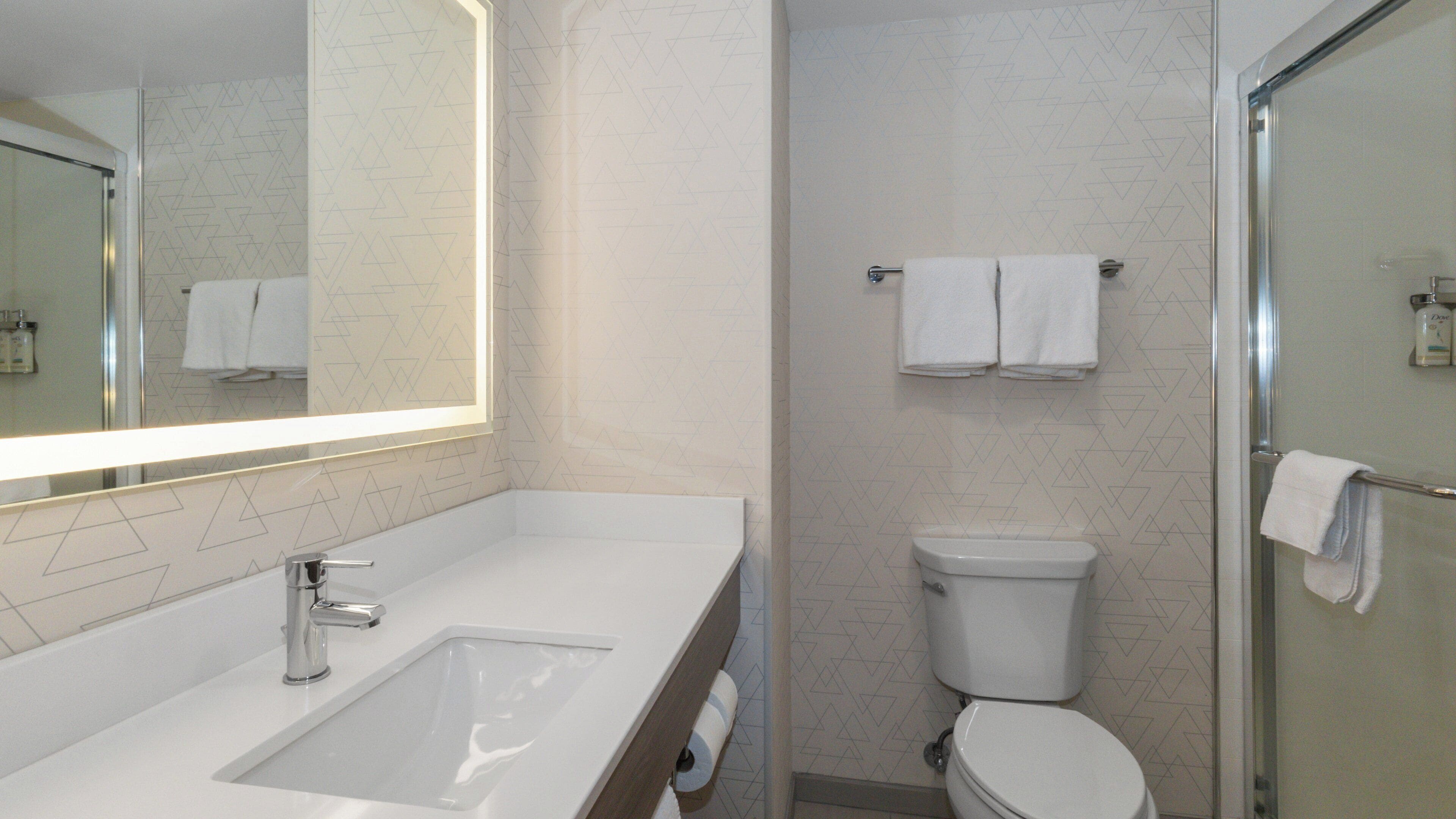 A bathroom with a white sink, mirror, toilet, and shower.