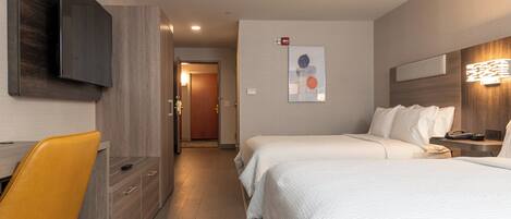 Una habitación de hotel con cama, escritorio, silla y televisión.