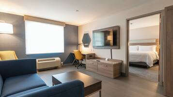 Een moderne hotelkamer met een bank, bureau, stoel, televisie, bed en raam.