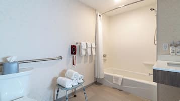 A modern bathroom with a shower, toilet, and a small step stool with towels.