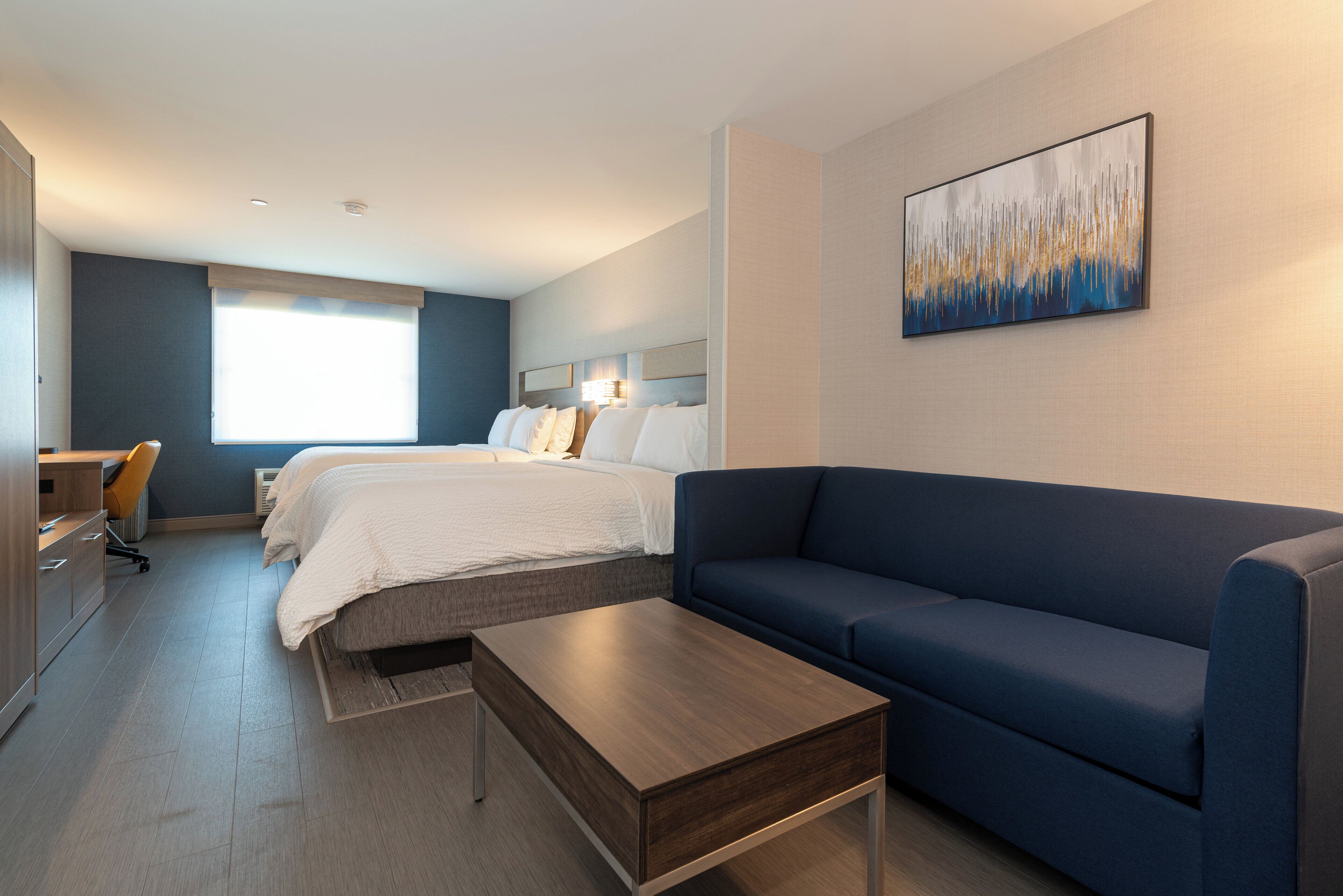 Et hotelværelse med en stor seng, en sofa, et skrivebord og et billede på væggen.
