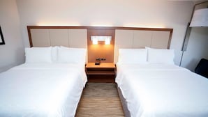 A hotel room with two single beds, a wooden headboard, a nightstand with a lamp, and a wall-mounted light fixture. - Holiday Inn Express Carlsbad by IHG (Carlsbad)