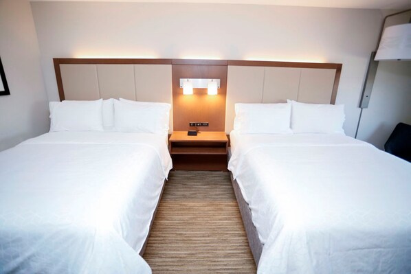 A hotel room with two single beds, a wooden headboard, a nightstand with a lamp, and a wall-mounted light fixture. - Holiday Inn Express Carlsbad by IHG (Carlsbad)