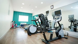 A fitness room with exercise equipment, a large mirror, and teal walls. - Holiday Inn Express Carlsbad by IHG (Carlsbad)